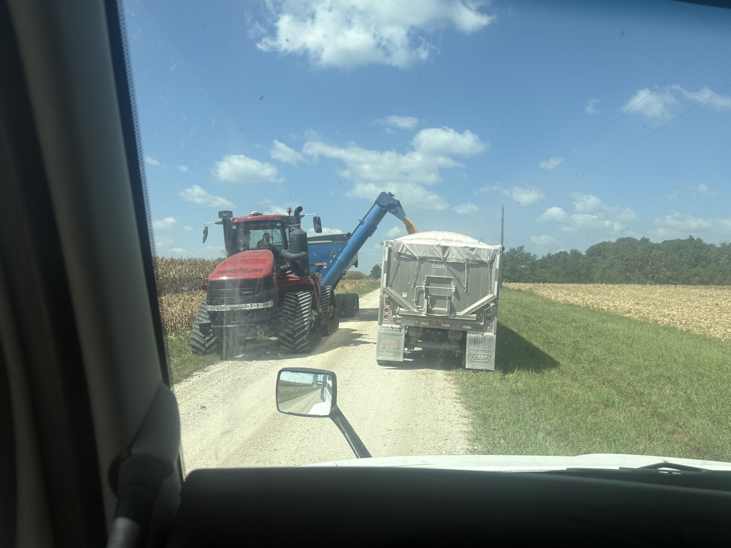 Tractor with grain cart unloading into semi tractor trailer in corn field